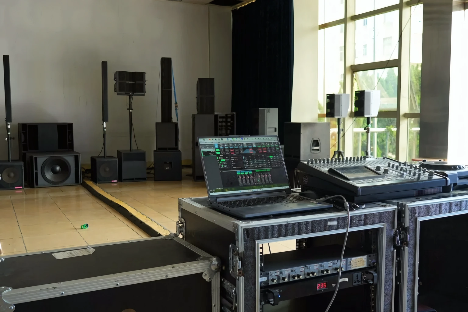 DSP tuning software running beside a mixing console in the listening room